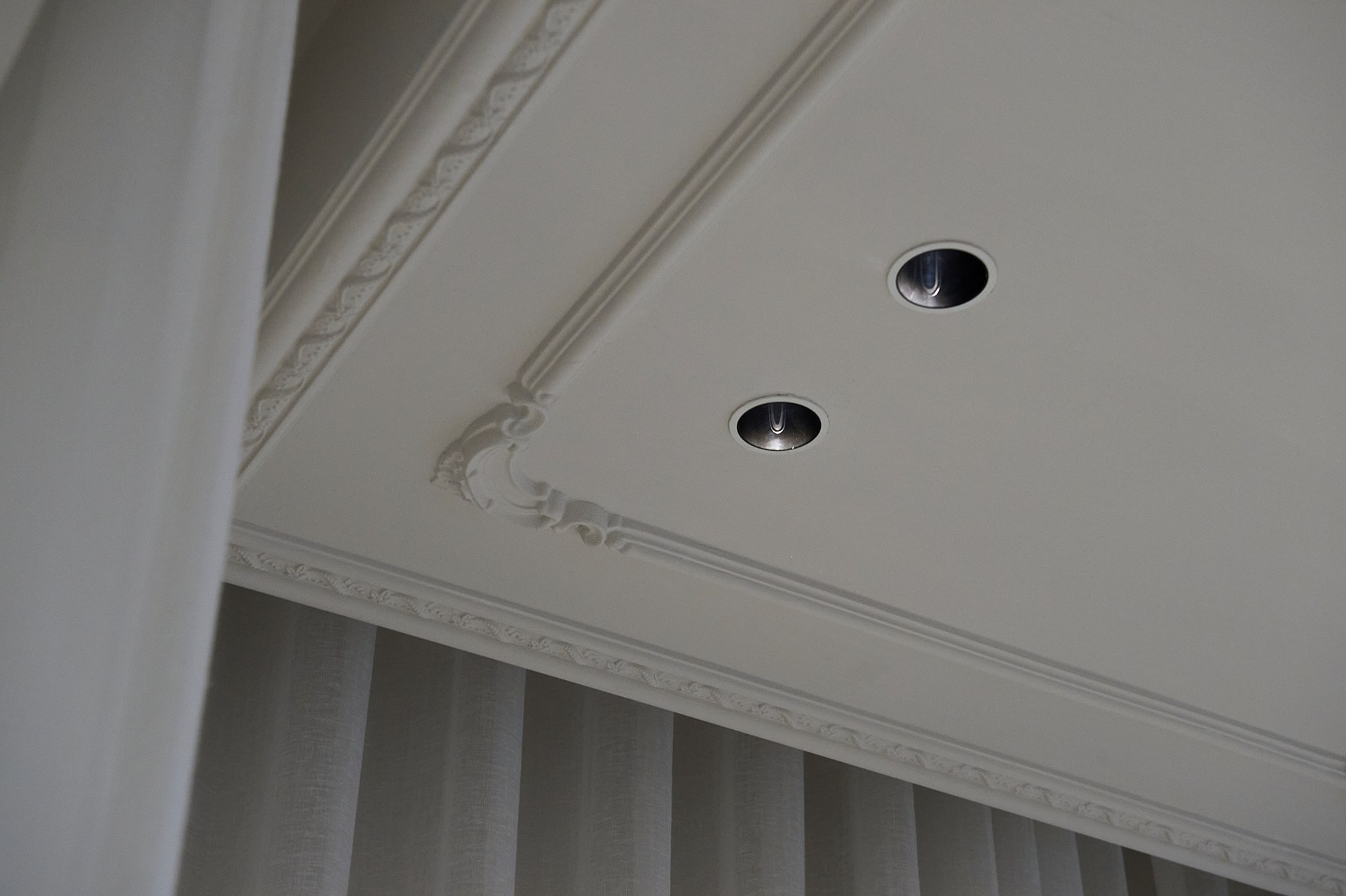 Cimaises décoratives fixées au plafond, qui mettent en valeur les spots encastrés et soulignent les proportions du plafond.