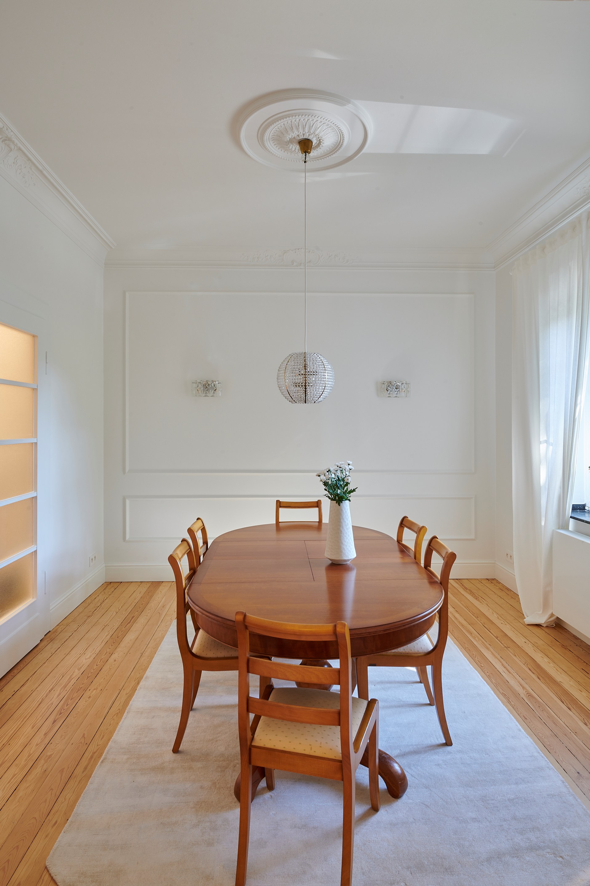 Rosace décorative et moulures qui rehaussent une salle à manger raffinée équipée d'un luminaire suspendu.